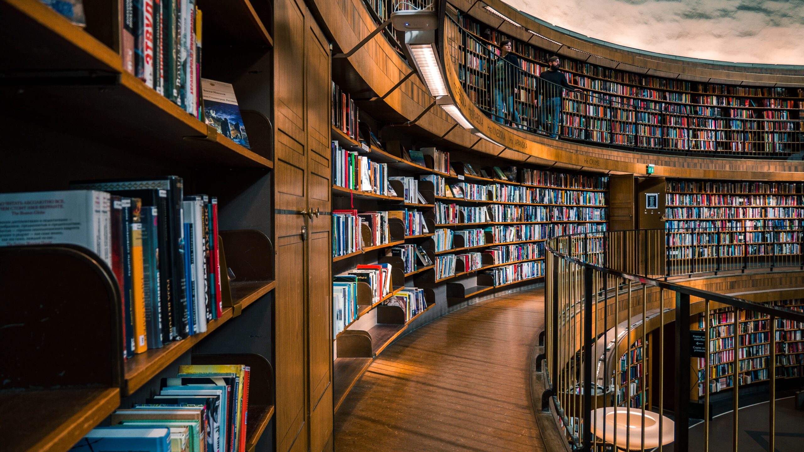 Photo of bookshelves and a wooden walkway on the second floor of a library